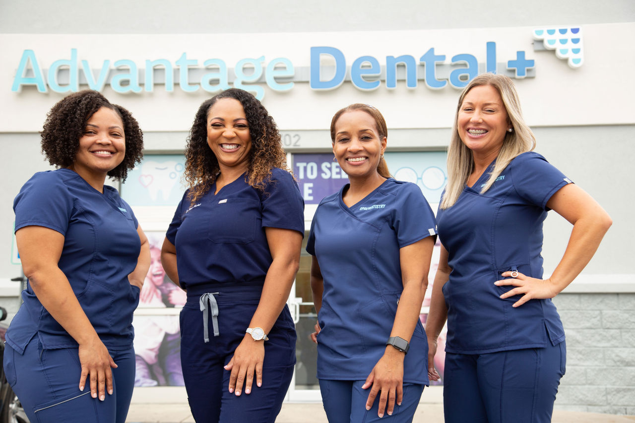 Advantage Dental employees smiling in front of a dental practice.