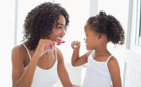 Mother teaching daughter good oral health habits.