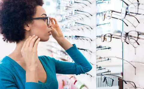 A woman trying on different pairs of eyeglasses.