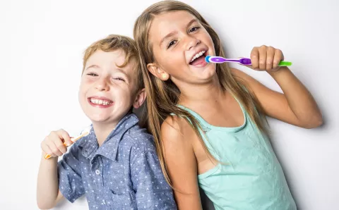 A boy and a girl excited to brush their teeth.