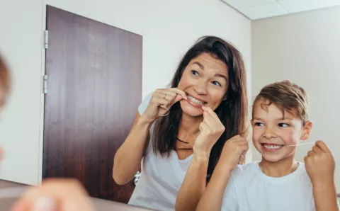 A mother flossing with her child.