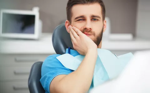 A stressed male patient feeling his jaw from dental pain.