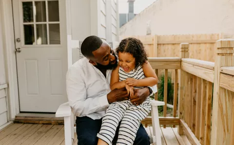 Man sitting on backyard porch playing with his daughter.