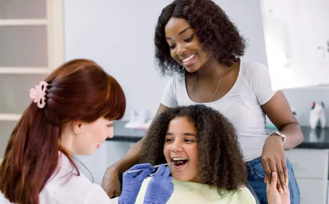A dentist creating a child-friendly dental care environment and leveraging anxiety-reducing methods with a pediatric patient.