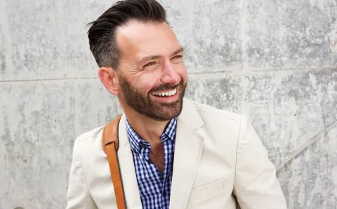 A man smiling outside of his office building during Men's Mental Health Month.