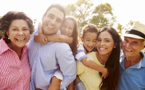 A family smiling together for a photo in a park.