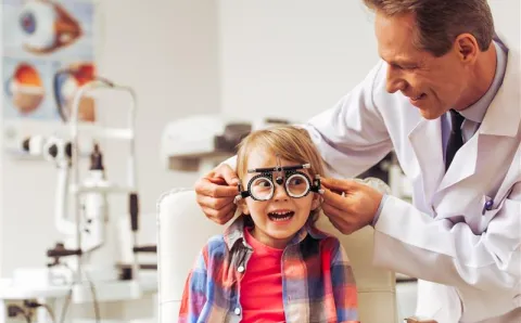 A child getting fitted for eyeglasses by an optometrist.